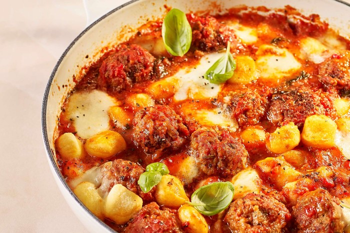 A one-pan meatball dish with drinks in the background