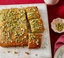 A rectangular sponge cake topped with chopped pistachios