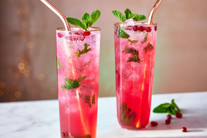 Two glasses of pink-hued mojito with mint and metal straws