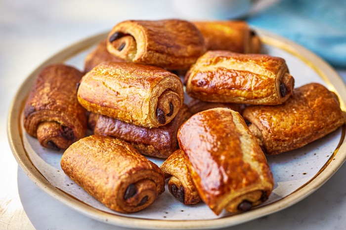 A plate of pain au chocolats with a mug of tea behind