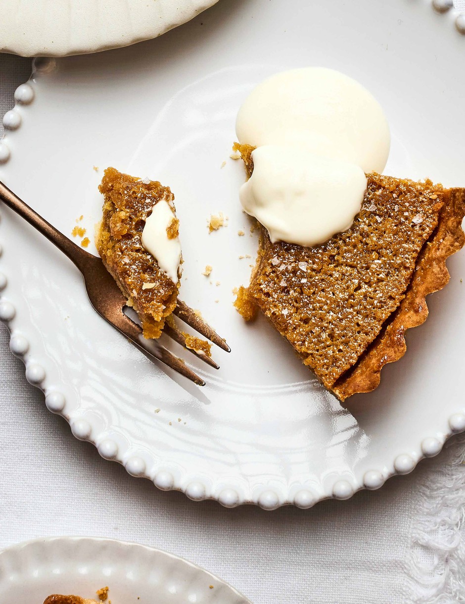 Brown butter miso treacle tart on a white plate and table