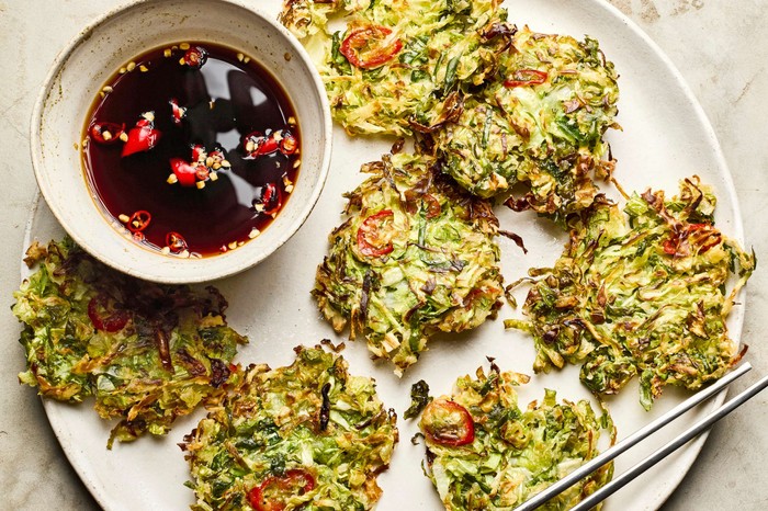 Mini cabbage pancakes on a plate with dipping sauce