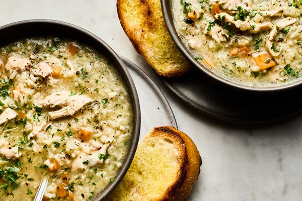 Two bowls of chicken and rice soup with toasted bread