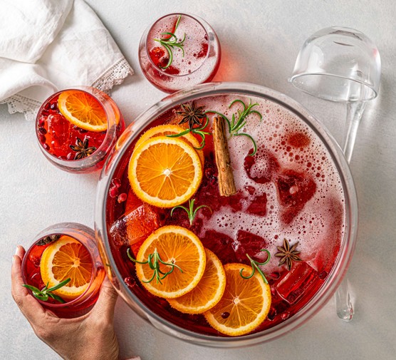 A bowl of Aperol punch with orange slices and cinnamon sticks floating on top