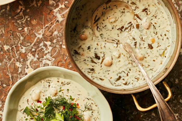 Two bowls of white soup decorated with herbs