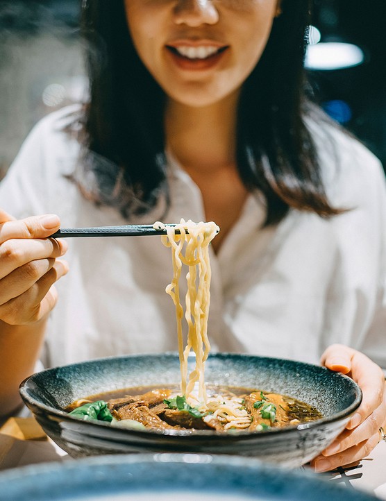 A woman eating a bowl of noodles