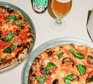 Two American-style pizzas with a glass of beer