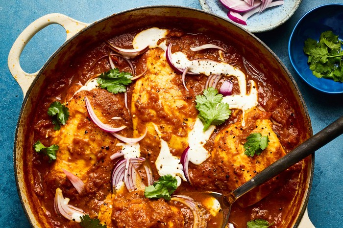 A large dish of fish masala with condiments on the side
