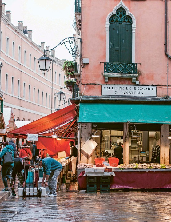 An outdoor Venetian store front, with workers organising produce