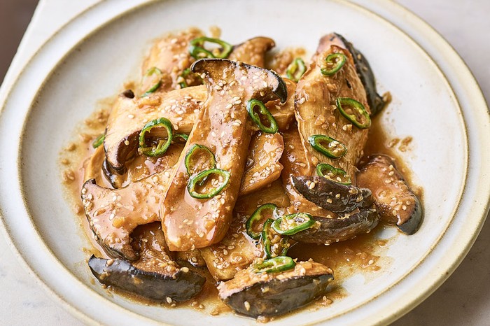 Plate with pile of mushrooms and buttery sauce topped with chillies