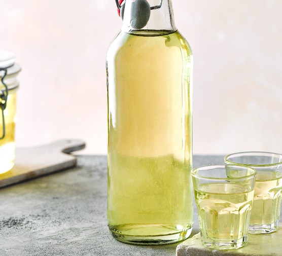 A bottle of homemade limoncello with two glasses on the side