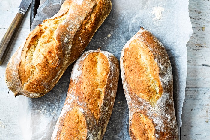 Three baguettes on a surface with a knife