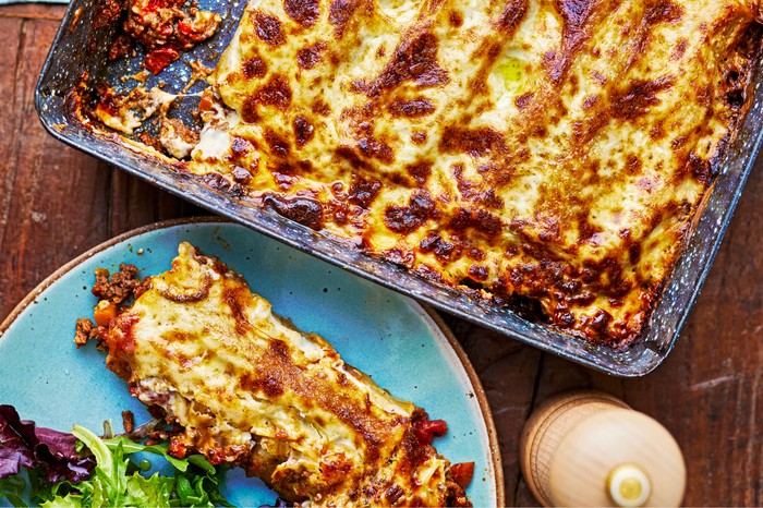 Beef cannelloni in a baking dish with a piece on the side on a plate