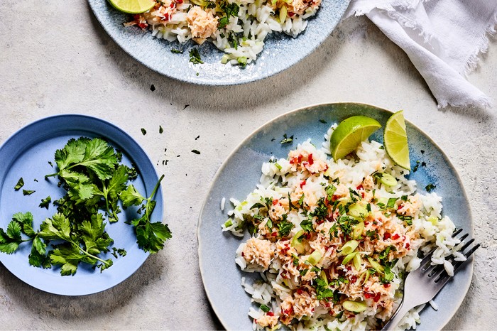 Two bowls of crab coconut rice with slices of lime on the side
