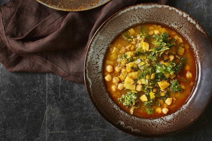 Two black bowls filled with green lentils and chickpeas in a broth