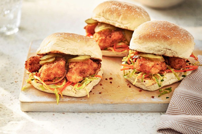 Three fish finger sandwiches on a wooden board