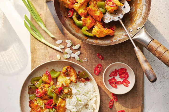 Gobi Manchurian in a wok with a full plate and spring onions on the side