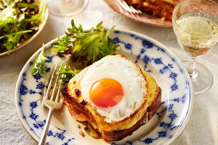 A croque madame topped with a fried egg with a salad on the side