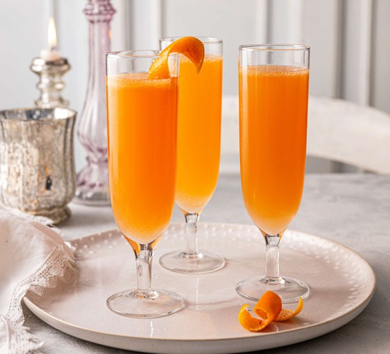 Three orange-coloured cocktails in champagne flutes