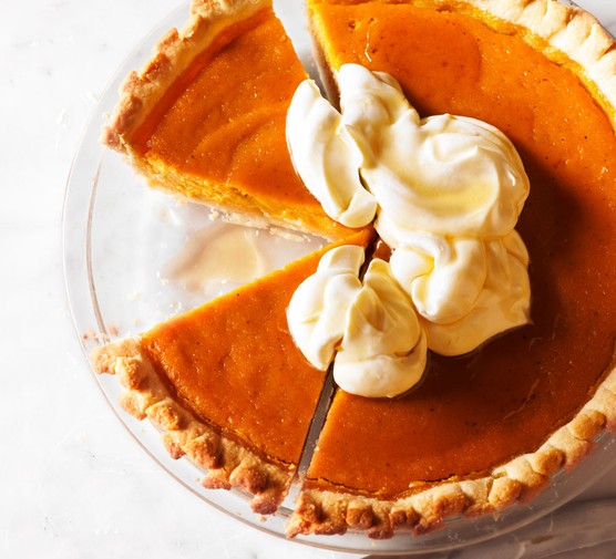 Pumpkin pie topped with cream, with one slice taken out