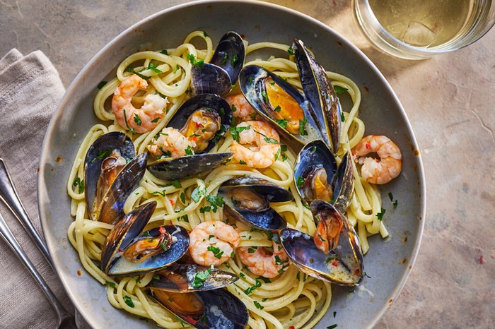 Linguine in a bowl topped with prawns and mussels