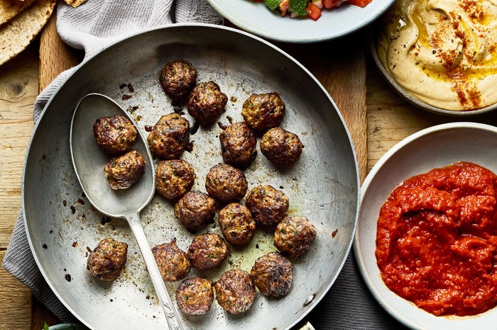 A serving platter of meatballs with dips on the side