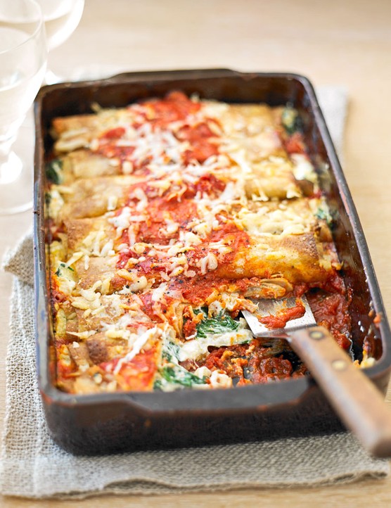 Tray of spinach and ricotta pancakes in tomato sauce
