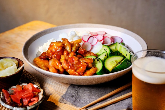 A plate of Japanese Teriyaki chicken with a glass of beer on the side