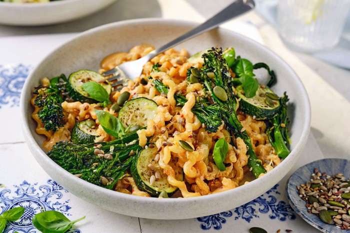 A bowl of tofu pasta with plenty of greens