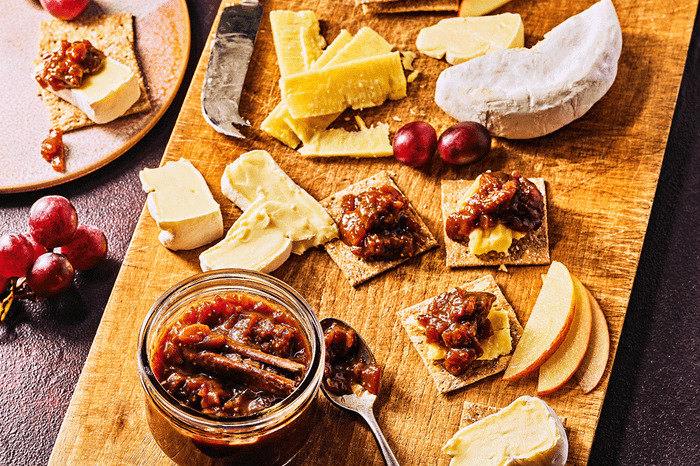 Orange and cinnamon fig chutney on a board with assorted cheeses and crackers