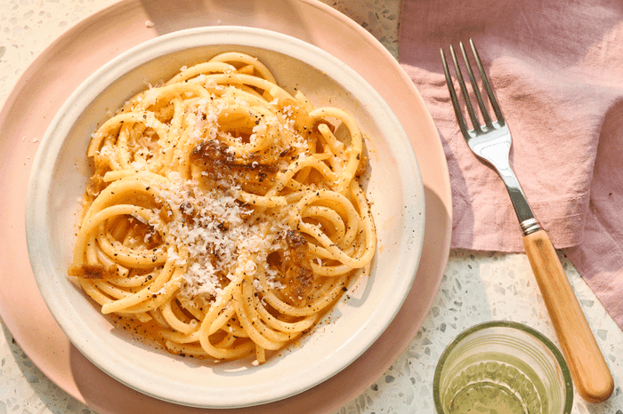 Bowl of spaghetti carbonara topped with grated parmesan