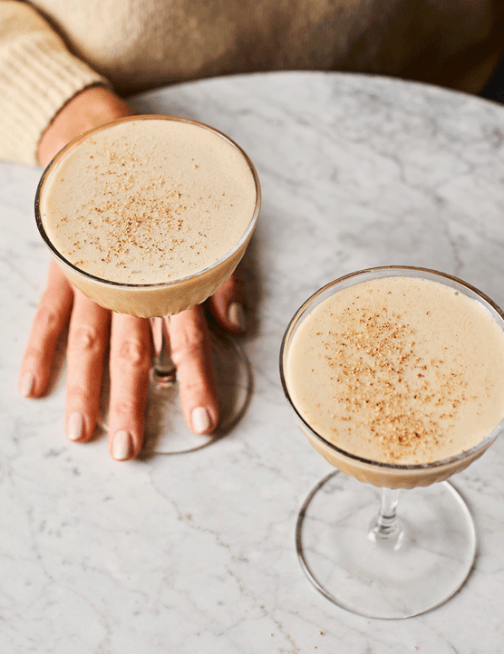 Two glasses of sherry flip cocktail on a marble table