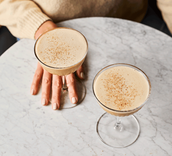 Two glasses of sherry flip cocktail on a marble table